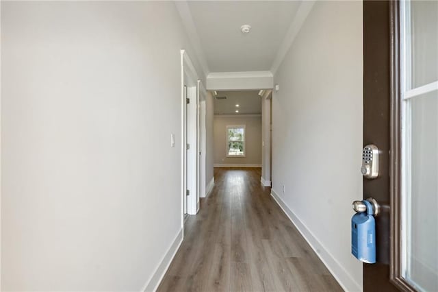 hallway featuring baseboards, wood finished floors, visible vents, and crown molding