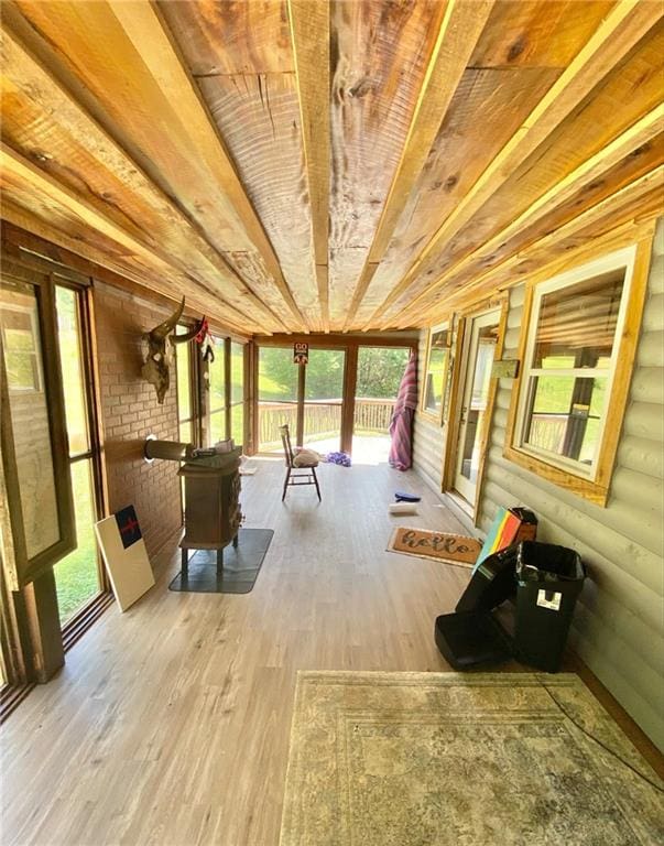 unfurnished sunroom featuring wooden ceiling, a healthy amount of sunlight, and a wood stove