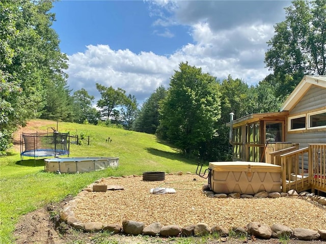 view of yard featuring a trampoline and a deck