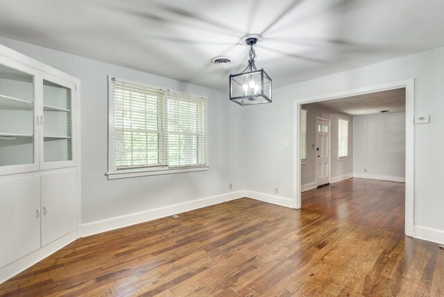 unfurnished dining area with dark wood-type flooring and a notable chandelier