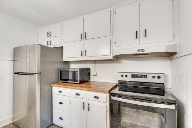 kitchen with appliances with stainless steel finishes, custom range hood, and white cabinetry