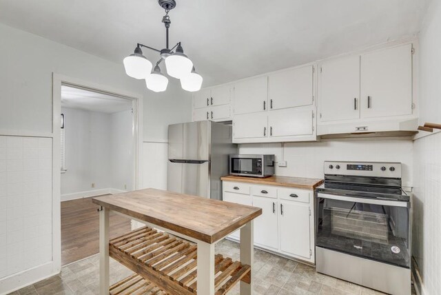 kitchen featuring appliances with stainless steel finishes, hanging light fixtures, a chandelier, and white cabinets