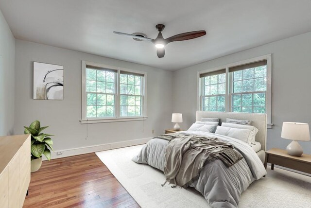 bedroom with multiple windows, ceiling fan, and hardwood / wood-style flooring