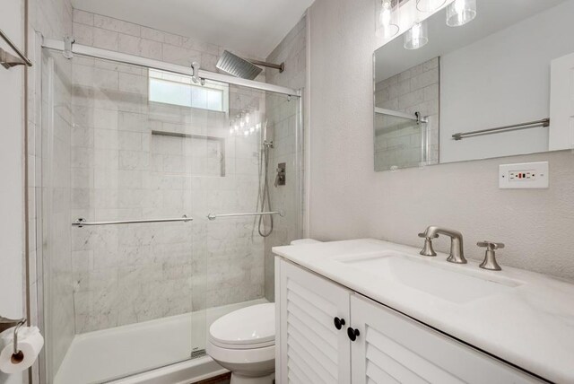 bathroom with vanity, toilet, and a shower with door