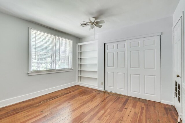 unfurnished bedroom with wood-type flooring, ceiling fan, and a closet