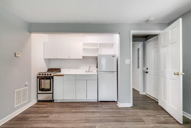 kitchen featuring light wood-type flooring, stainless steel electric stove, sink, and white refrigerator