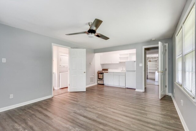 unfurnished bedroom featuring multiple windows, light wood-type flooring, and white refrigerator