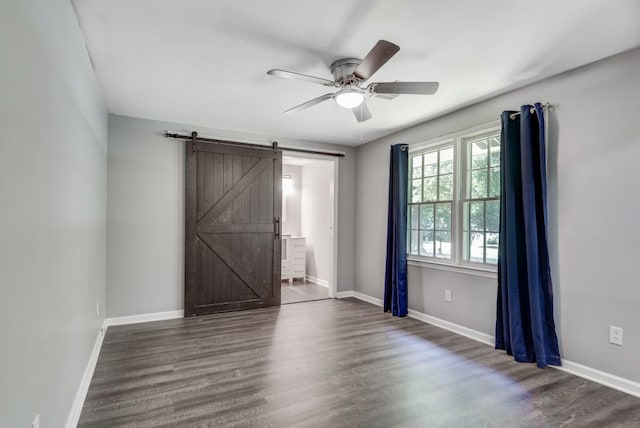 unfurnished room featuring ceiling fan, dark wood-type flooring, and a barn door