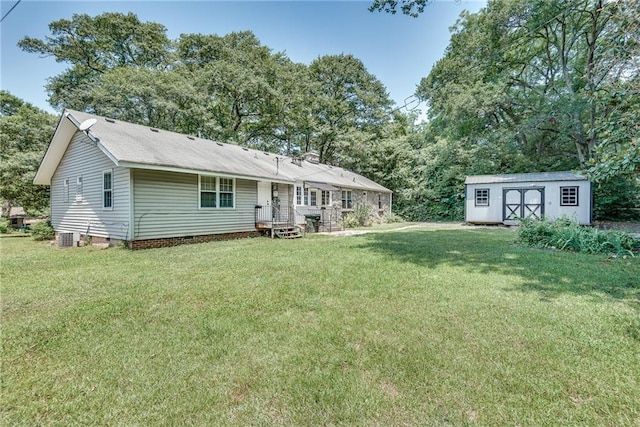 back of house with a lawn and a storage unit