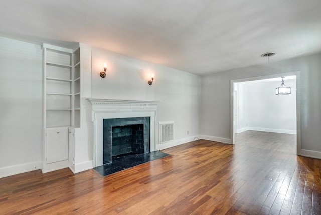 unfurnished living room with a high end fireplace, a chandelier, and hardwood / wood-style floors