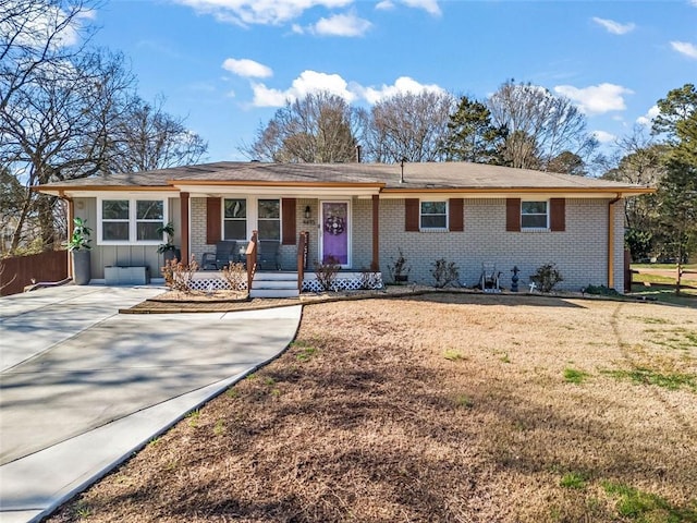 ranch-style house featuring board and batten siding, a porch, brick siding, and a front yard