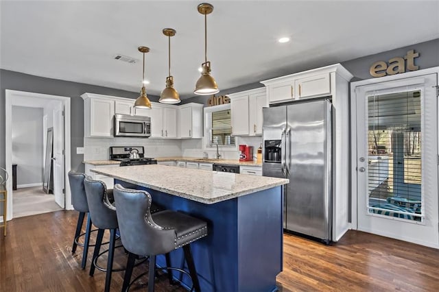 kitchen featuring visible vents, a sink, white cabinets, appliances with stainless steel finishes, and a center island