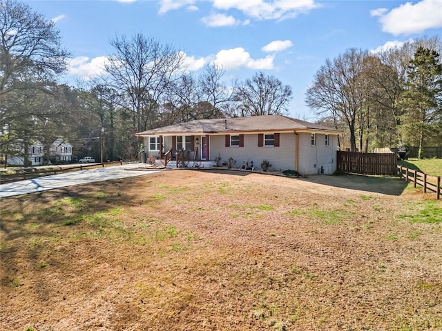 back of property featuring covered porch, a yard, fence, and brick siding