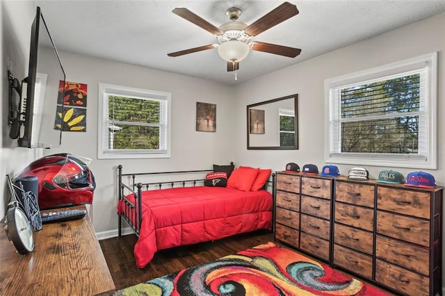 bedroom with a textured ceiling, a ceiling fan, baseboards, and wood finished floors