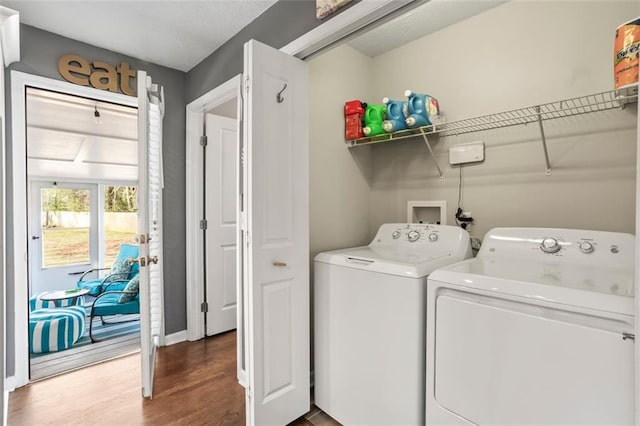 clothes washing area featuring wood finished floors, laundry area, and washer and clothes dryer