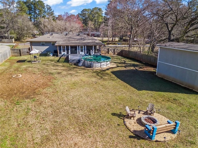 view of yard featuring a fenced in pool, an outbuilding, a fire pit, and a fenced backyard