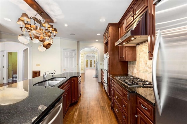 kitchen featuring tasteful backsplash, stainless steel appliances, hanging light fixtures, dark wood-type flooring, and dark stone countertops