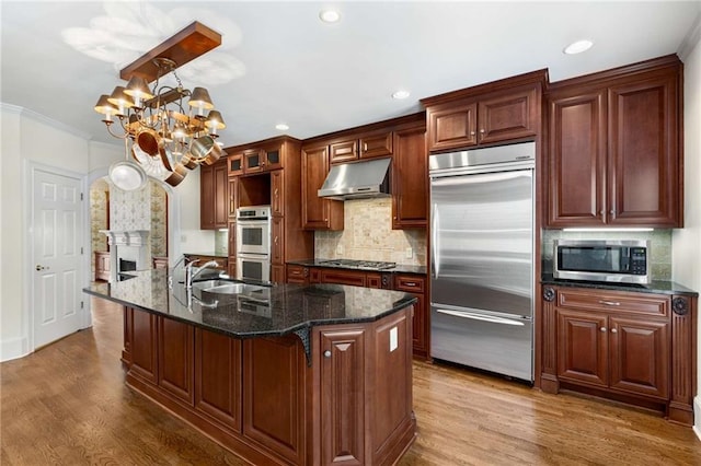 kitchen featuring stainless steel appliances, a center island with sink, a notable chandelier, and hardwood / wood-style floors