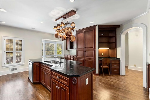 kitchen featuring dark wood-type flooring, sink, a chandelier, an island with sink, and ornamental molding