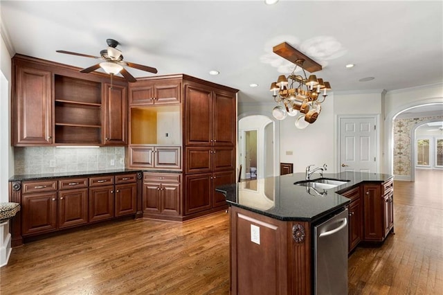 kitchen with sink, ceiling fan with notable chandelier, an island with sink, crown molding, and dark wood-type flooring