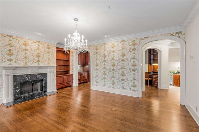 unfurnished living room with a high end fireplace, built in features, crown molding, and wood-type flooring