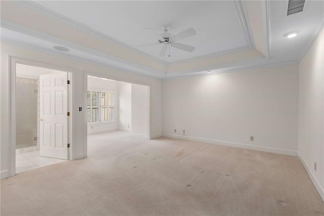 spare room featuring ornamental molding, a raised ceiling, light carpet, and ceiling fan