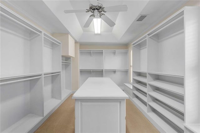 walk in closet with a tray ceiling, light carpet, and ceiling fan