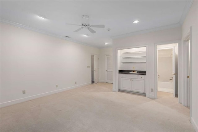 unfurnished living room with indoor wet bar, light colored carpet, ceiling fan, and crown molding