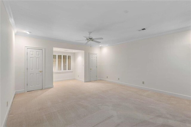 spare room featuring light colored carpet, ceiling fan, and crown molding