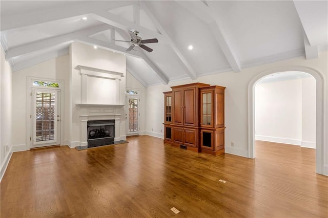 unfurnished living room with hardwood / wood-style flooring, vaulted ceiling with beams, and ceiling fan