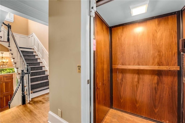 interior details with an inviting chandelier, elevator, and wood-type flooring