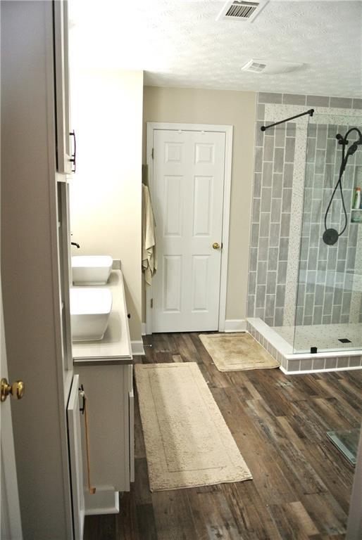 3824 Smith Creek Ct, Buford, GA 30519 - full bathroom featuring a stall shower, double vanity, wood finished floors, and a textured ceiling