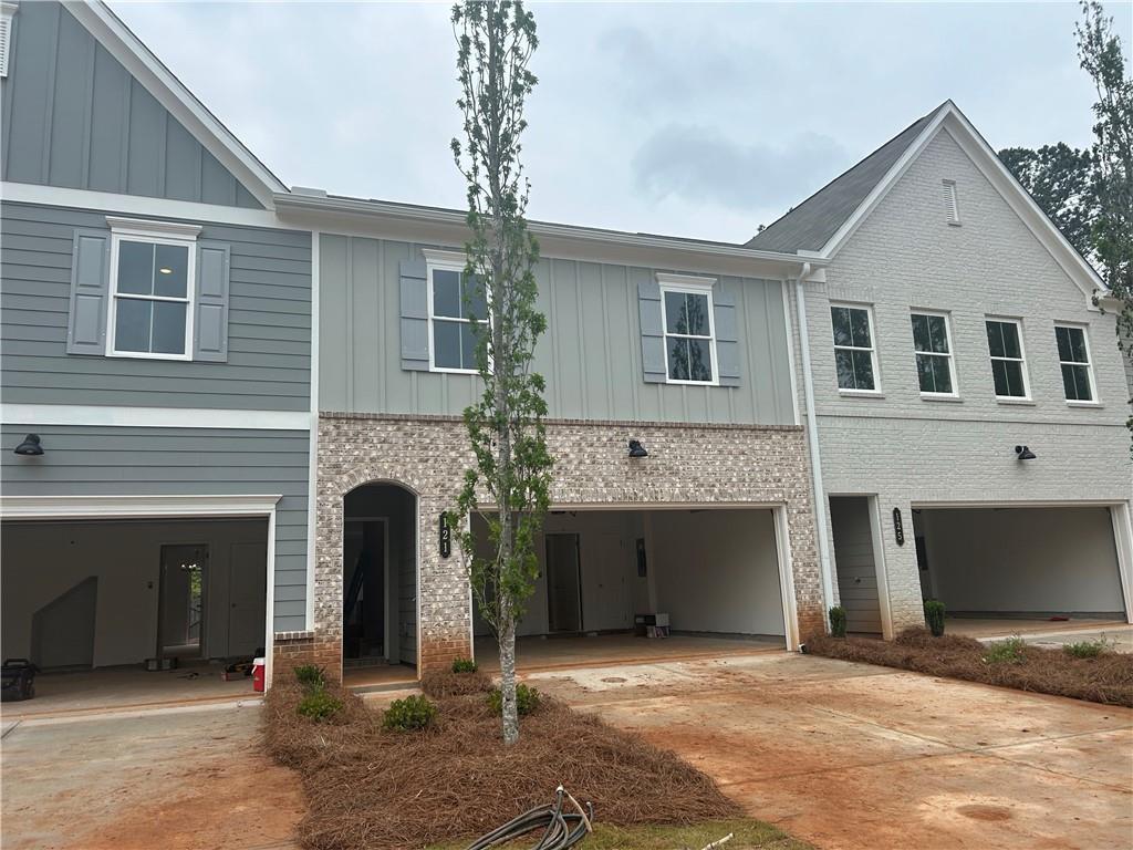 view of front of home with board and batten siding, driveway, and brick siding