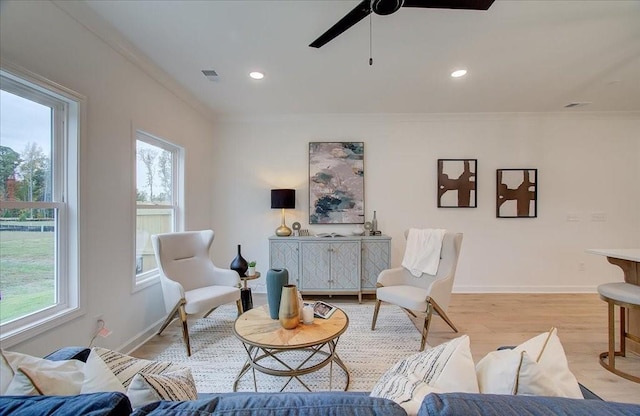 living room featuring crown molding, baseboards, ceiling fan, recessed lighting, and light wood-style flooring