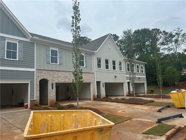 view of front of property featuring an attached garage, board and batten siding, concrete driveway, and brick siding