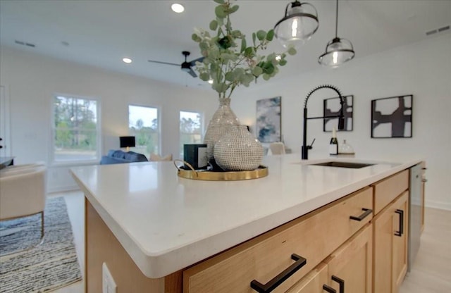 kitchen with a sink, light brown cabinets, a kitchen island with sink, open floor plan, and visible vents