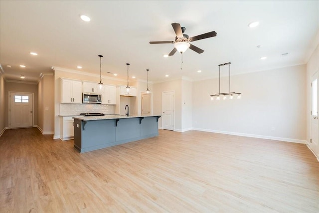 kitchen with recessed lighting, stainless steel microwave, a breakfast bar area, and white cabinetry