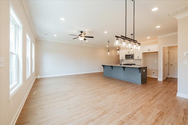 kitchen with crown molding, stainless steel microwave, ceiling fan, and a kitchen bar