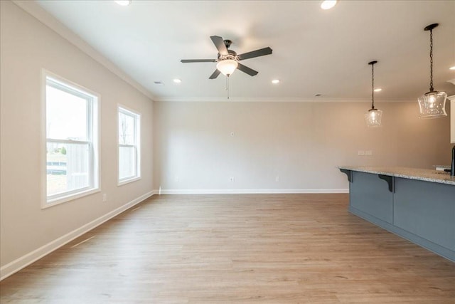 unfurnished living room featuring light wood-style floors, ornamental molding, and ceiling fan