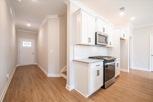 kitchen with crown molding, appliances with stainless steel finishes, light wood-style floors, and visible vents