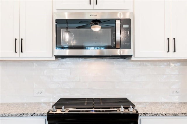 kitchen featuring a ceiling fan, appliances with stainless steel finishes, backsplash, and white cabinets