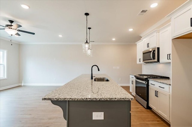 kitchen featuring a sink, light wood finished floors, stainless steel appliances, a ceiling fan, and visible vents