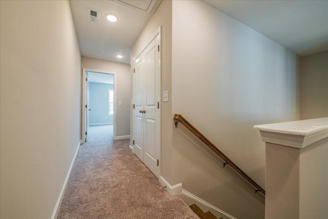 hall featuring carpet floors, visible vents, baseboards, and an upstairs landing