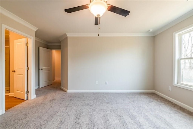 spare room with carpet floors, ornamental molding, baseboards, and ceiling fan