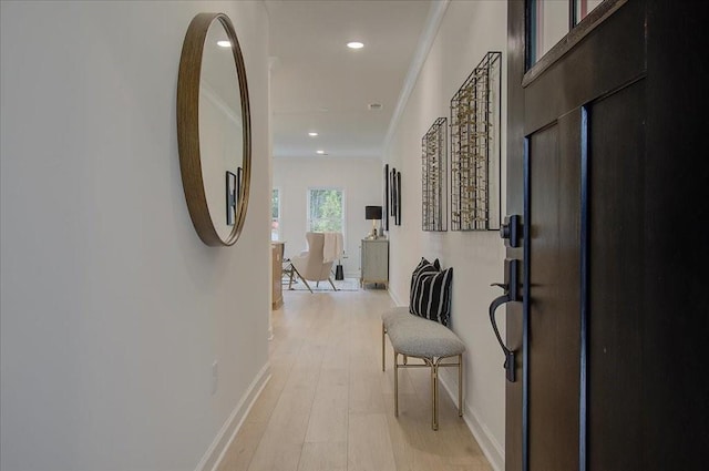 corridor featuring light wood-style floors, baseboards, ornamental molding, and recessed lighting