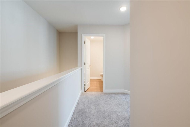 hallway with recessed lighting, baseboards, and light carpet