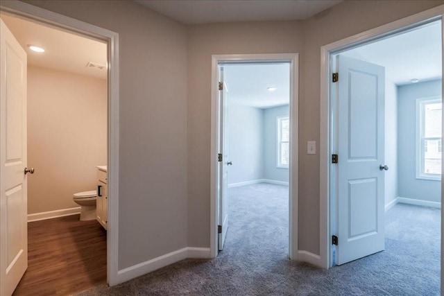 hallway featuring baseboards, carpet floors, and visible vents