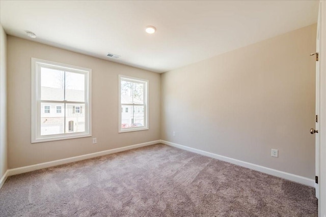 unfurnished room featuring baseboards, visible vents, and carpet
