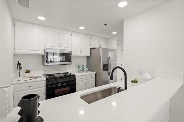 kitchen with kitchen peninsula, appliances with stainless steel finishes, white cabinetry, and sink