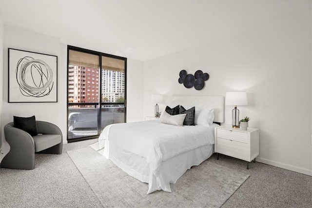 bedroom featuring access to exterior, light carpet, and a wall of windows